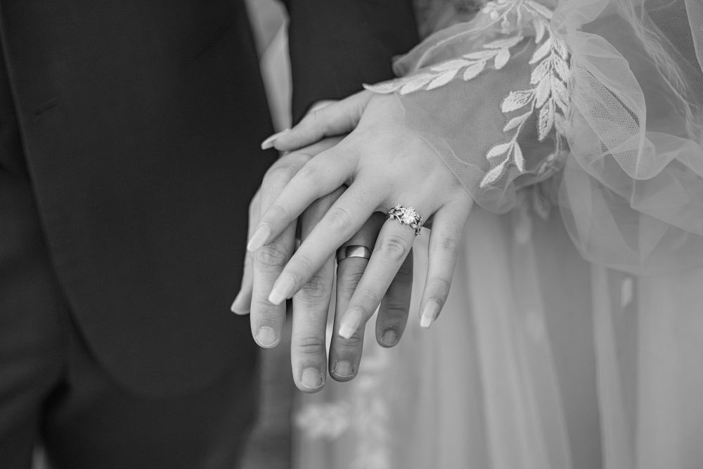 Someone holding hands with gold sparkly spiral rings and lace in a romantic wedding setting.