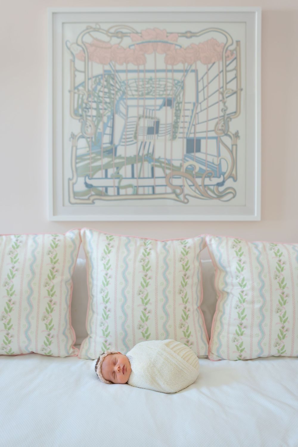 A series of soft white nursery decorations and artwork hang above a crib with green accents.