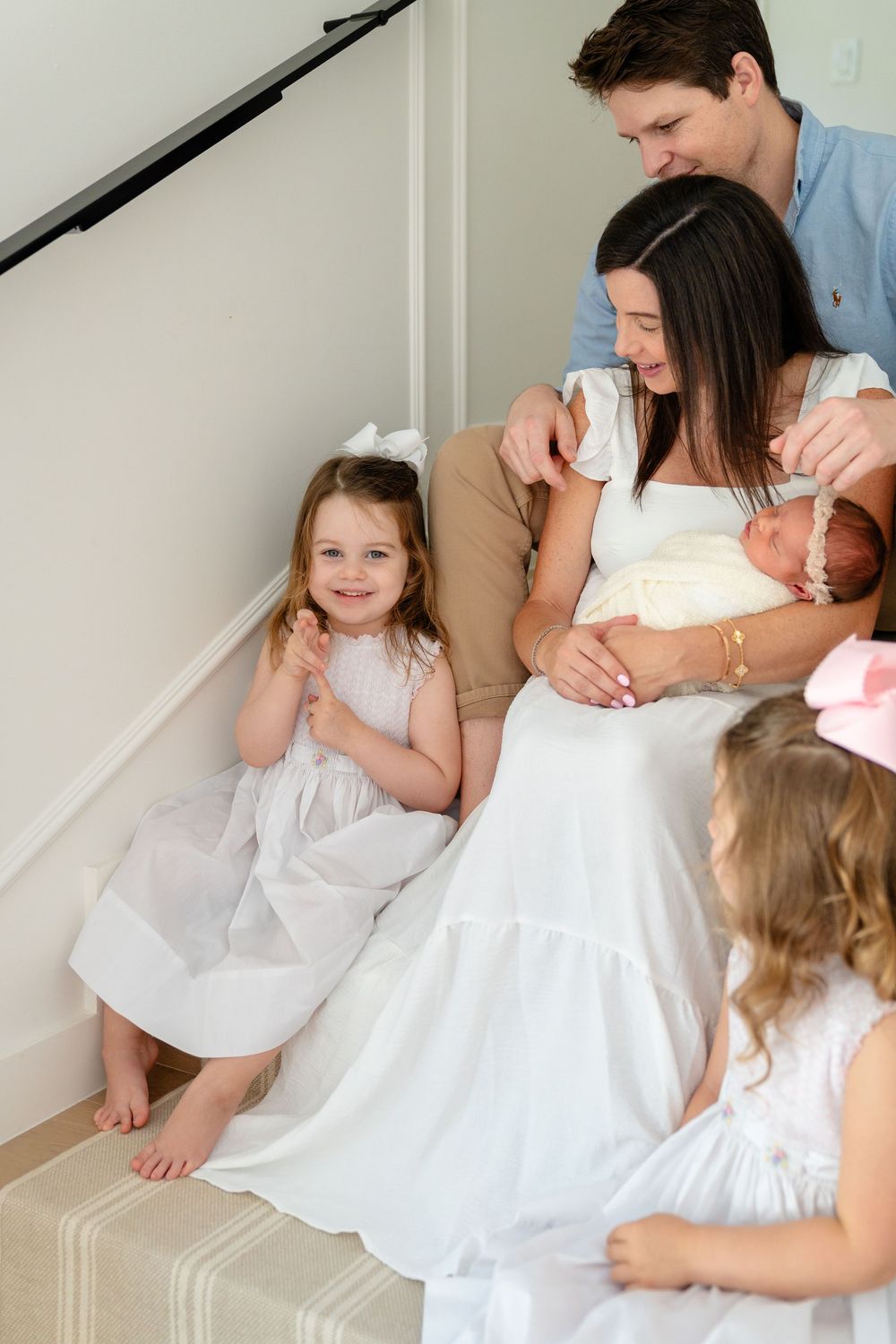 A loving family moment captured in white dresses sitting together on stairs.