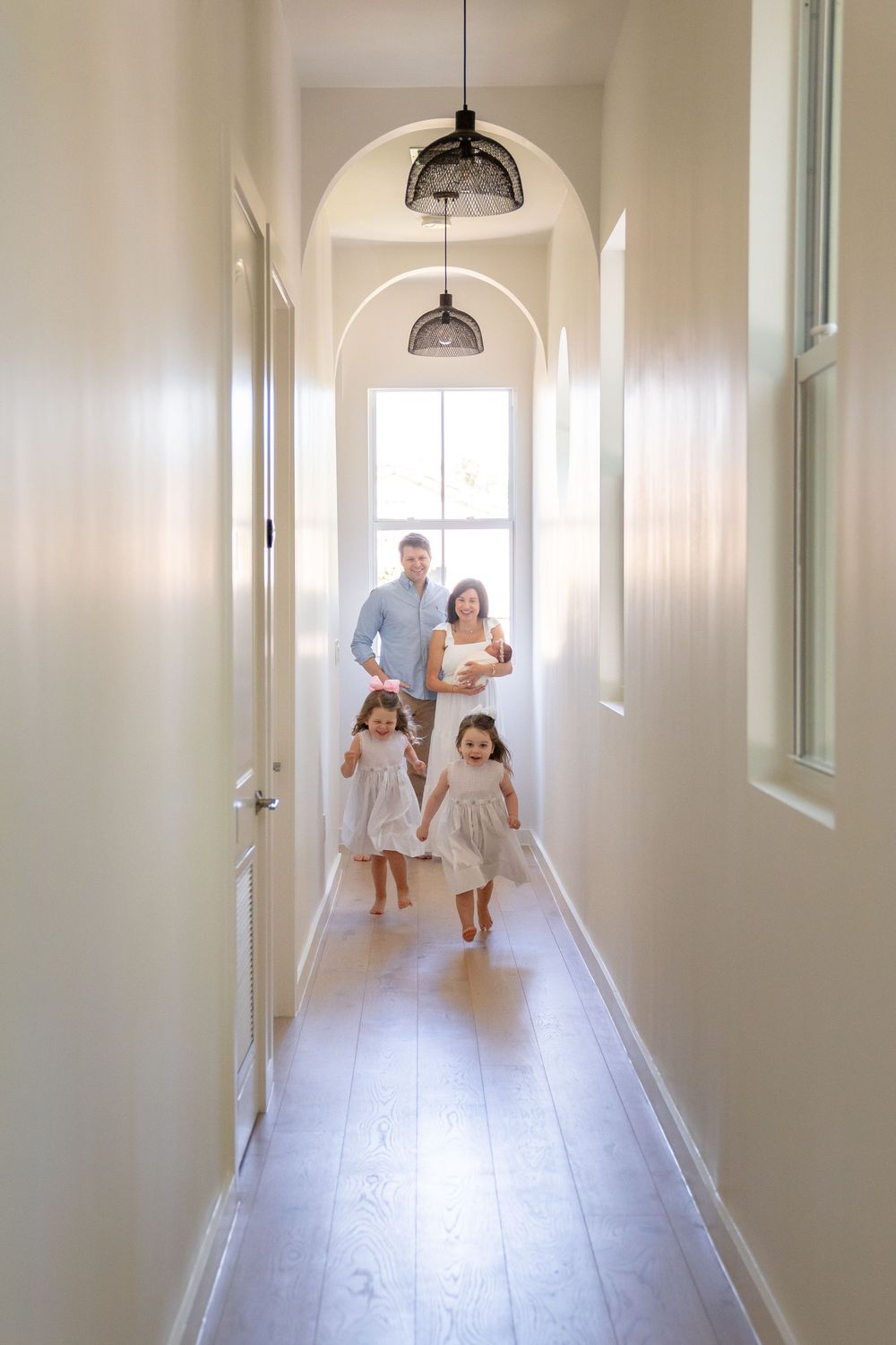 Bright white hallway with pendant lights and hardwood floors showing a sequence of movement.