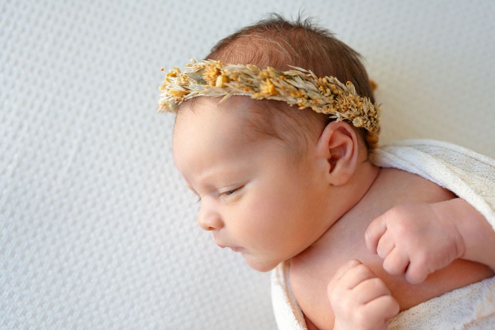 A series of adorable newborn baby photos with a gold leaf crown headband arranged in a horizontal collage.