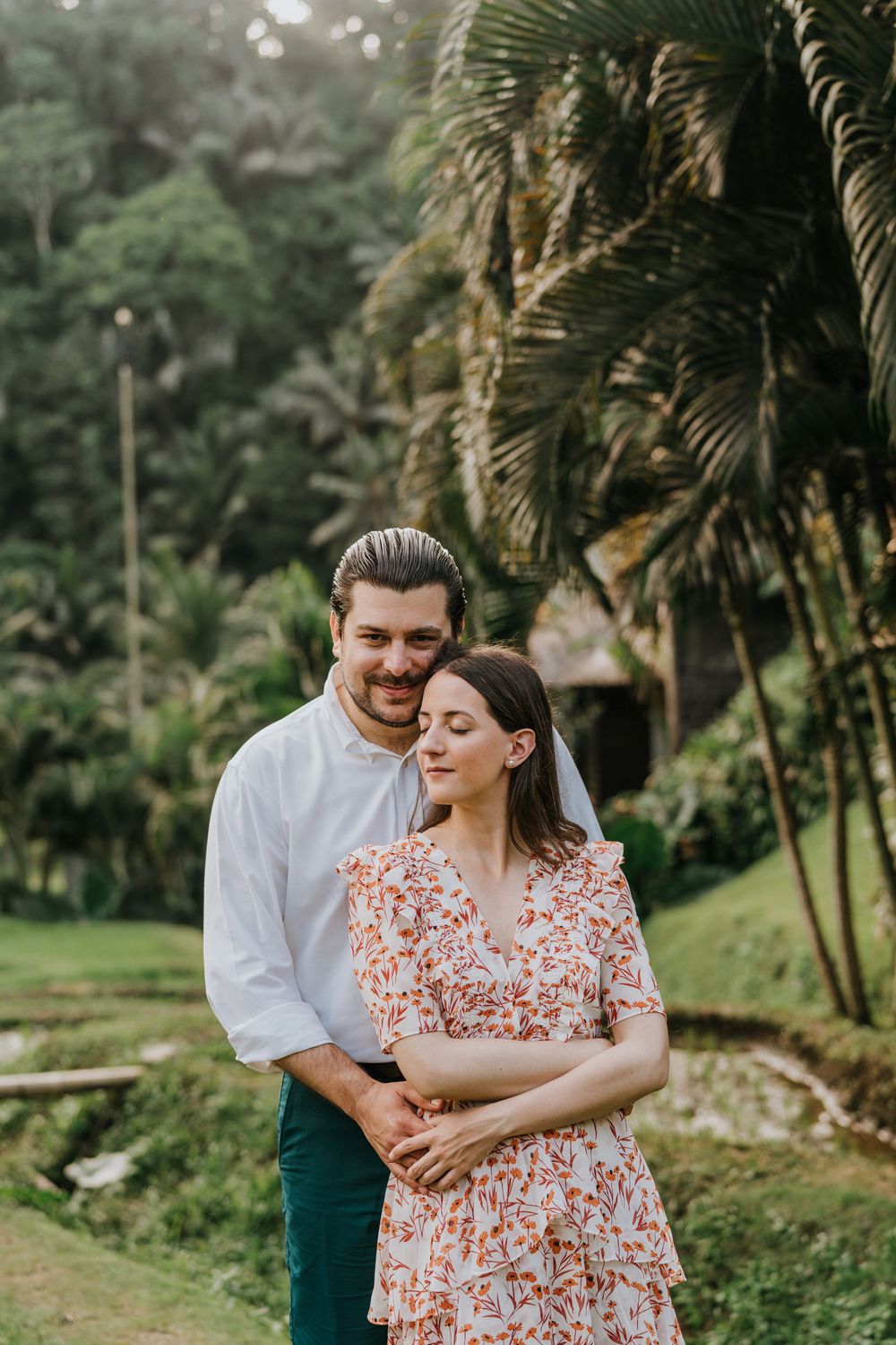 A loving moment shared among palm trees in a tropical garden setting.