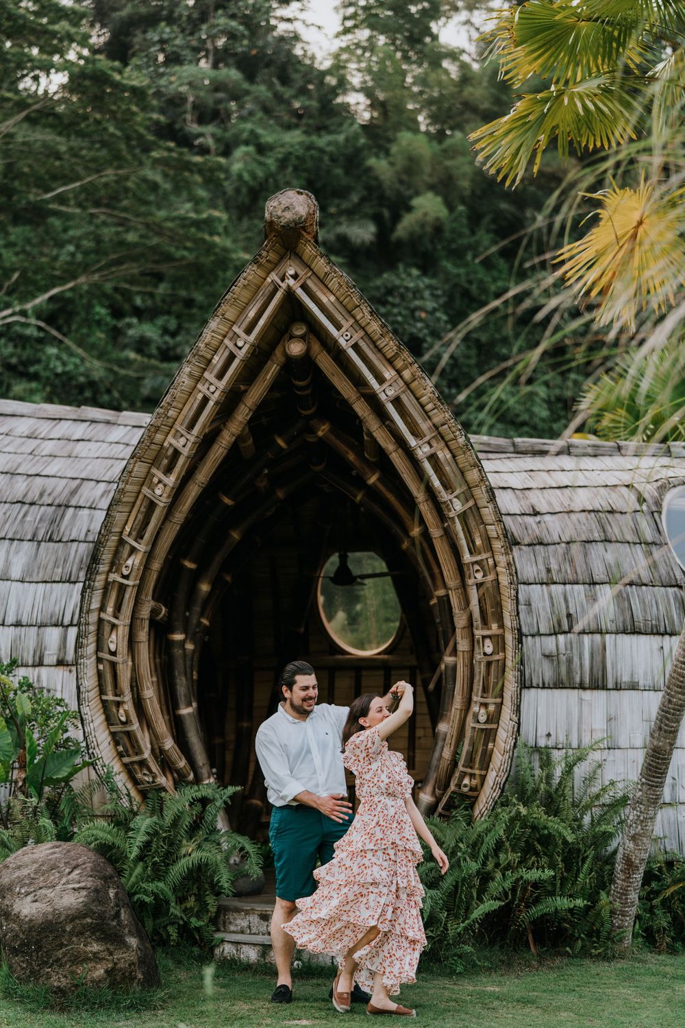 A romantic moment in front of an ornate bamboo archway with circular windows.