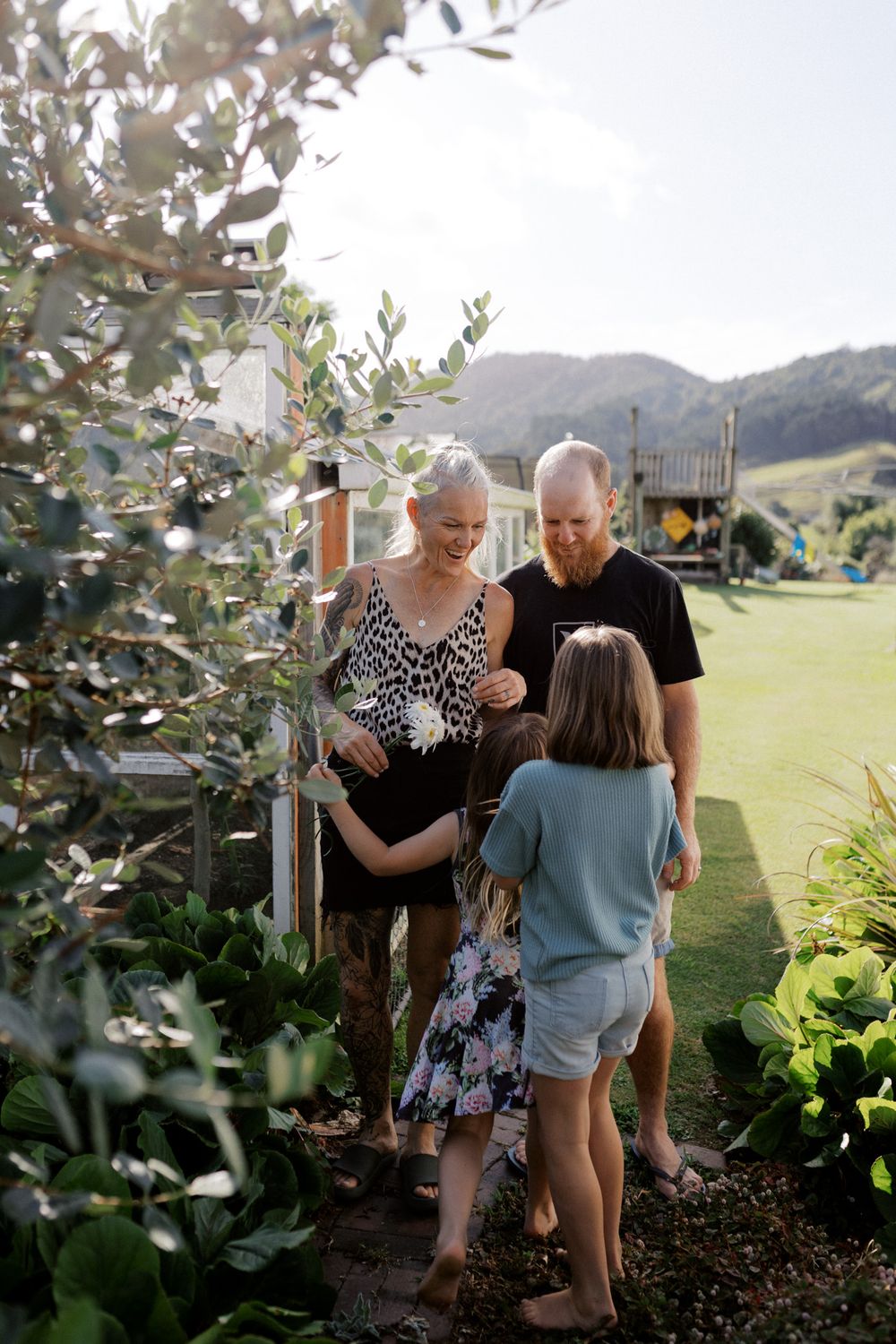 Three sequential photos show people sharing a tender moment together in a garden setting with mountains in the background.