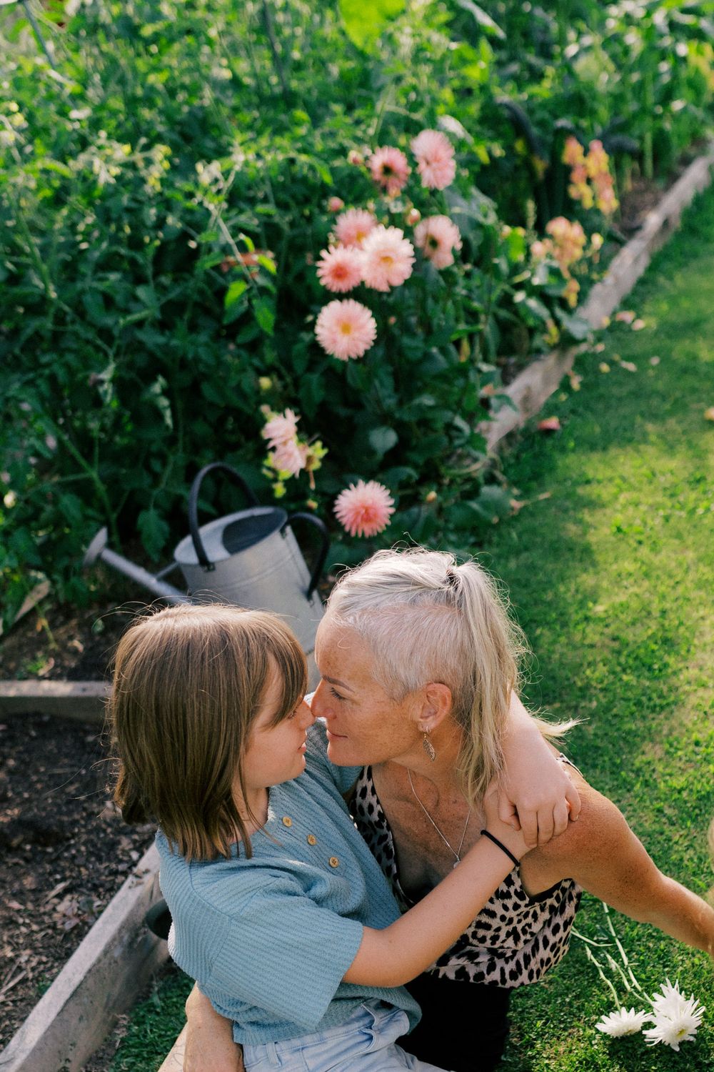 A tender family moment shared in a blooming garden with pink flowers and greenery.