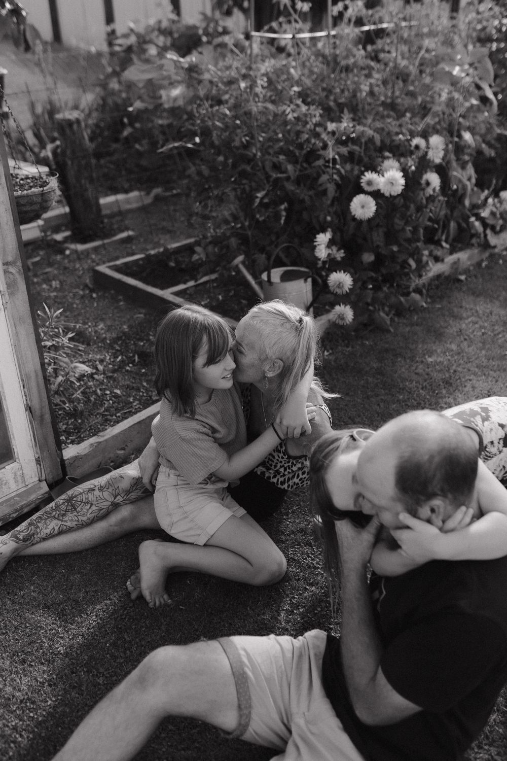 People relaxing in a garden with flowers and greenery captured in black and white photography.