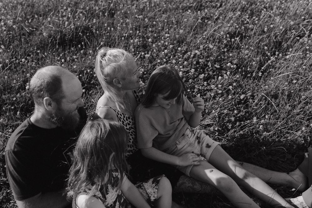 A candid family moment captured outdoors against lush garden foliage.