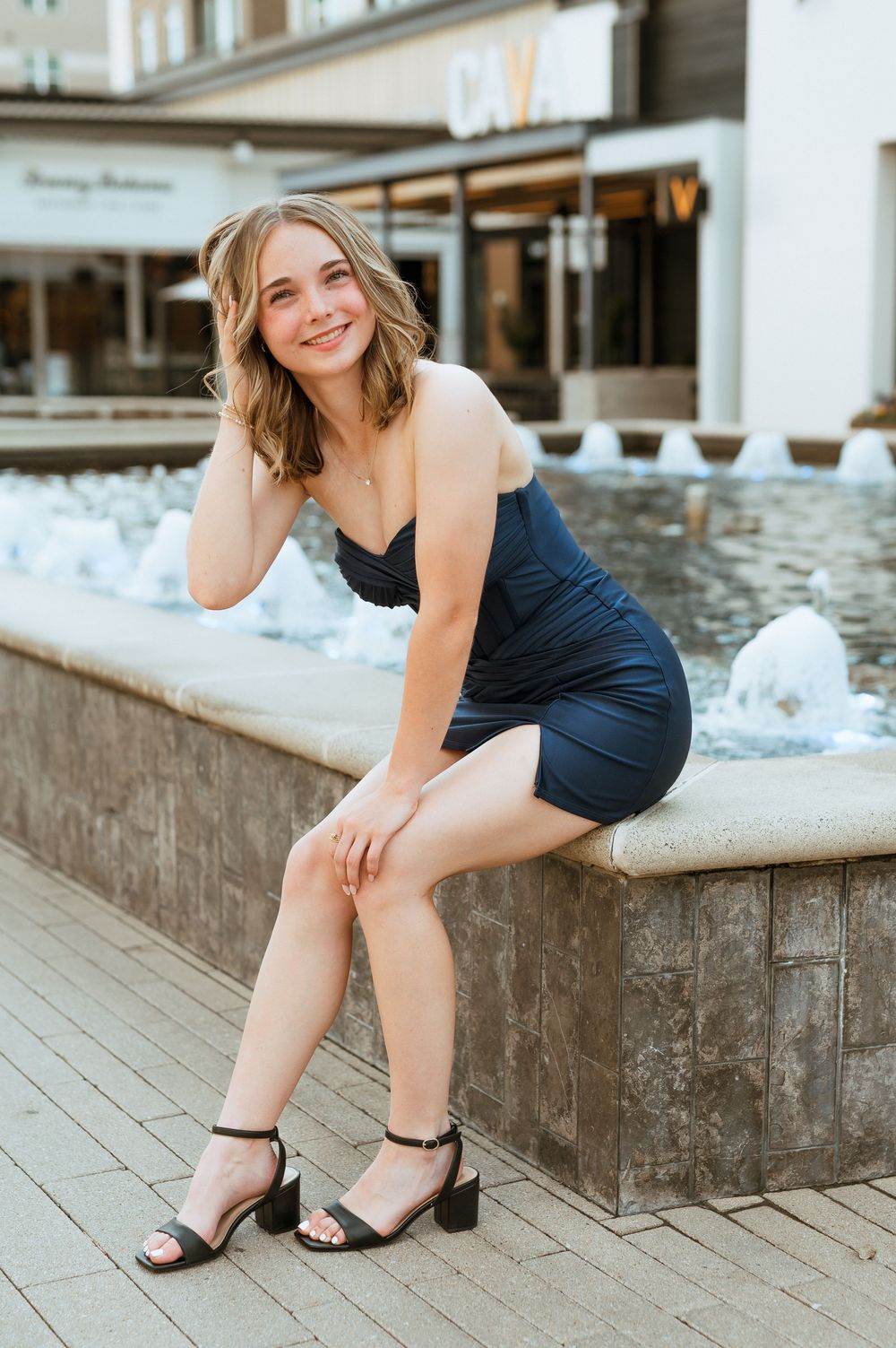 Navy dress and heels ensemble photographed near stone fountain during photoshoot.