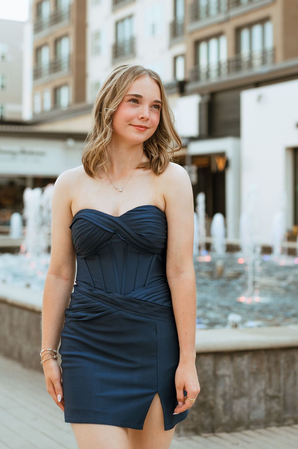 A series of five photos showing someone posing in a navy blue strapless dress against an urban backdrop.