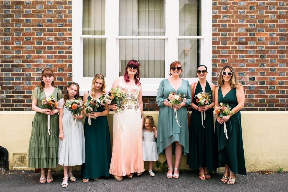 Bride with bridesmaids in green dresses holding bouquets outside in Brighton.