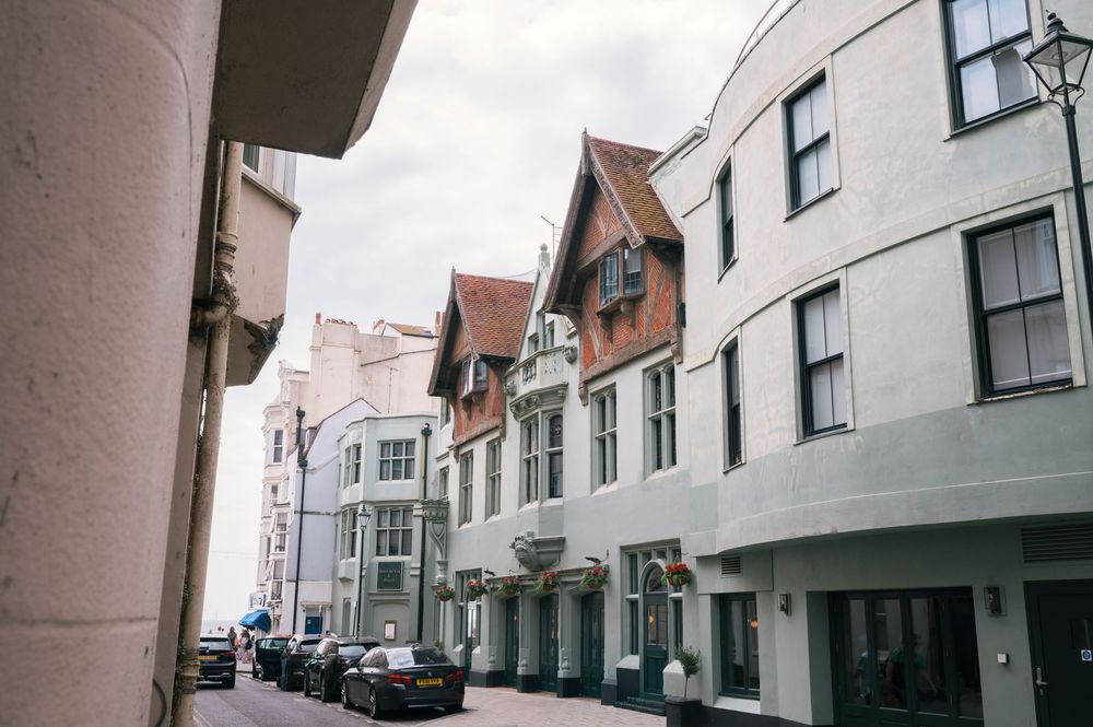 Brighton streets lined with historic buildings featuring gabled roofs and white facades under an overcast sky. Hotel Du Vin Brighton.
