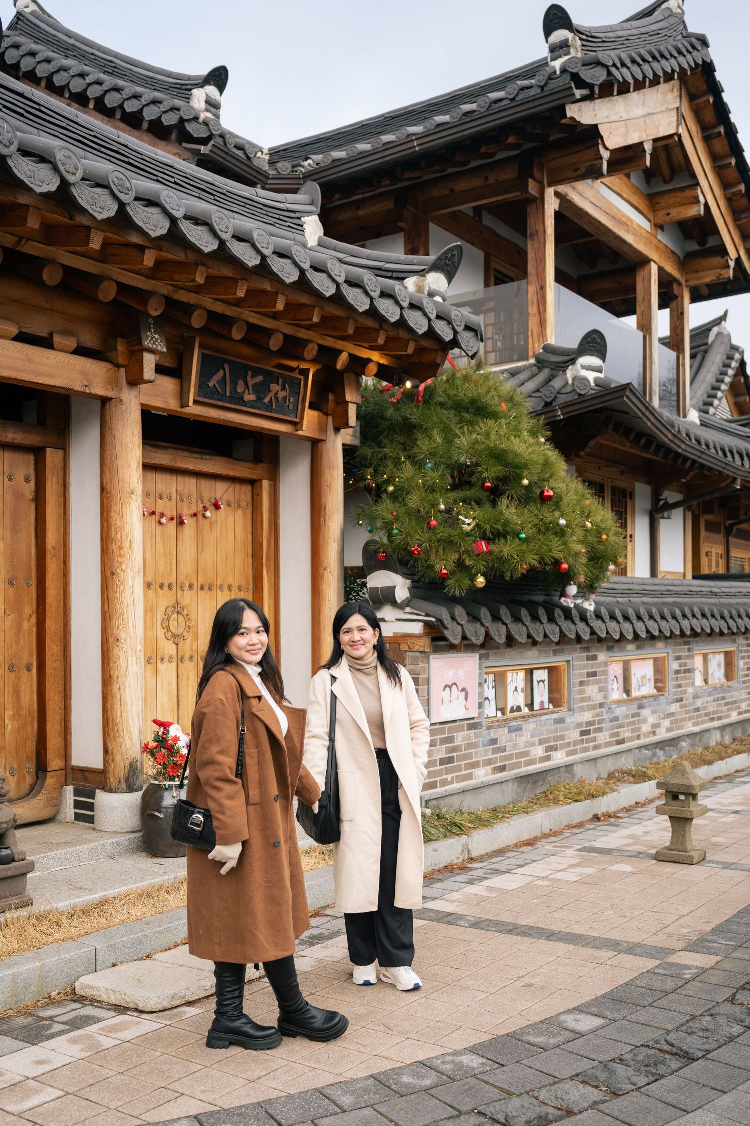Traditional Korean hanok building with curved tile roof and wooden pillars, featuring winter holiday decorations.