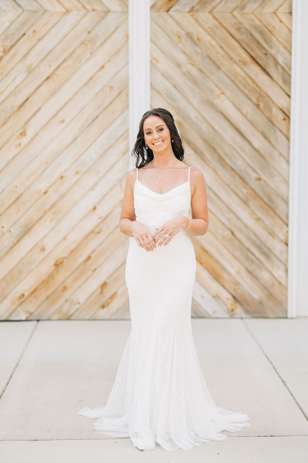 A classic white wedding dress flows elegantly against a wooden chevron wall backdrop.