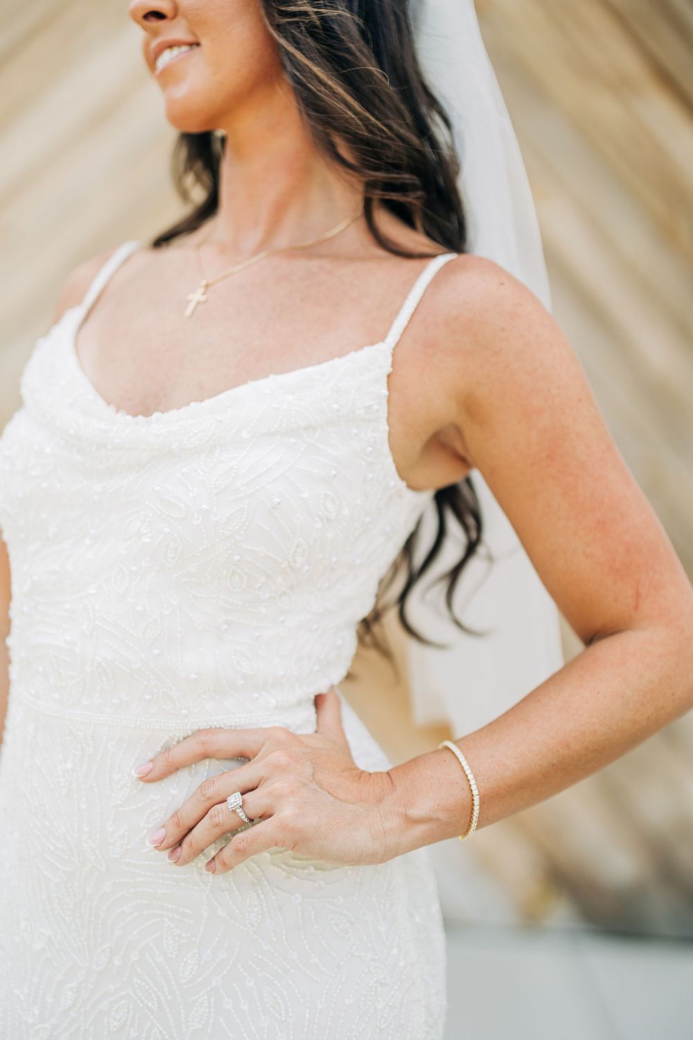 Bride in sleeveless white wedding dress shows off delicate beaded details and lace trim in elegant bridal portrait series.