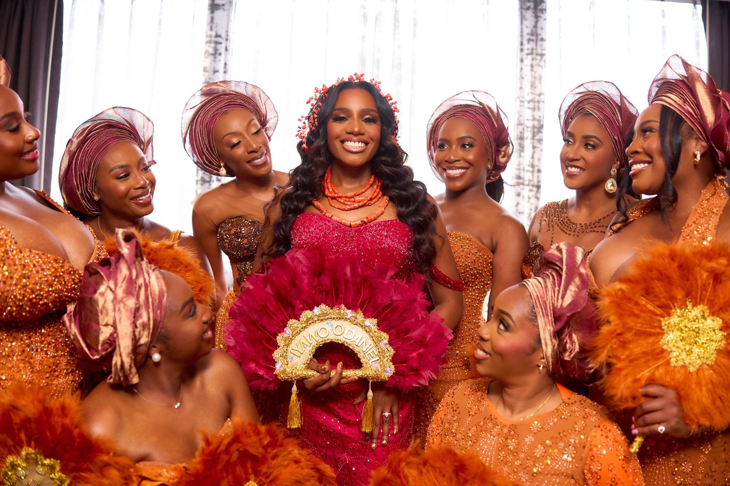 Festive group in vibrant orange and red attire smiling and celebrating together.