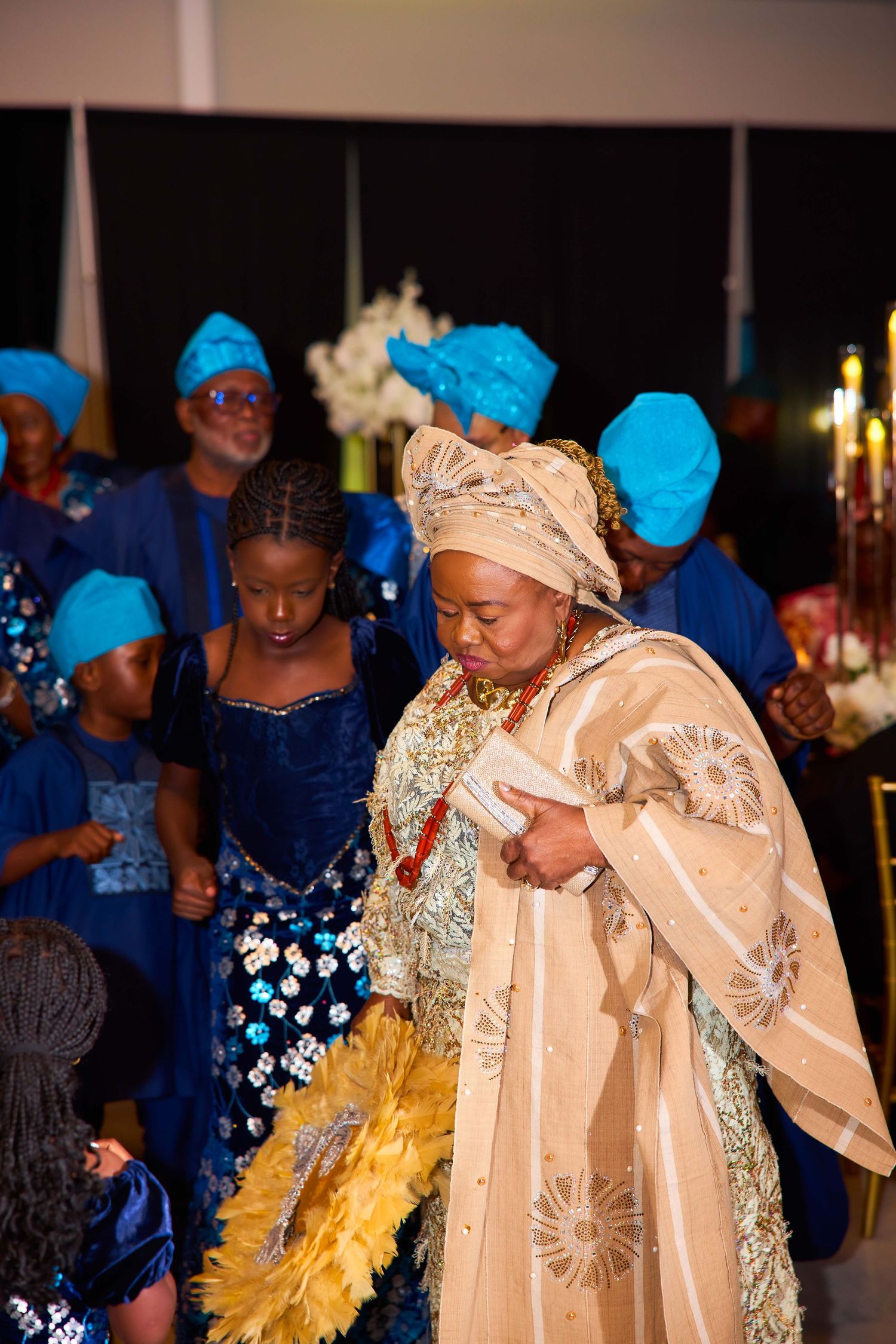 Traditional West African celebration with people wearing colorful blue and gold attire dancing at a cultural event.