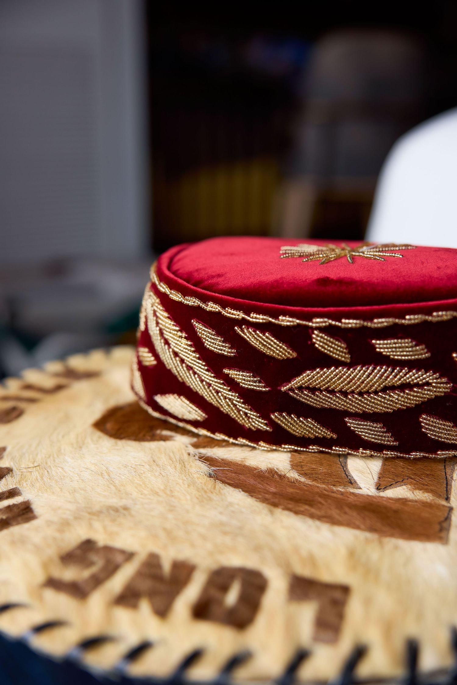 Close-up detail of an ornate burgundy and gold embroidered traditional cultural garment.