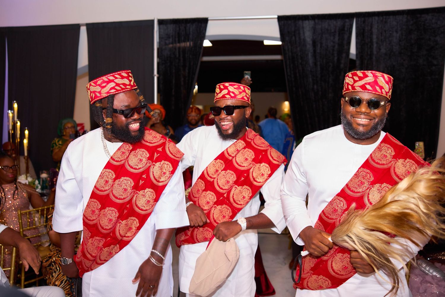 A line of people wearing matching red and white patterned head coverings and white shirts stand together at an event.