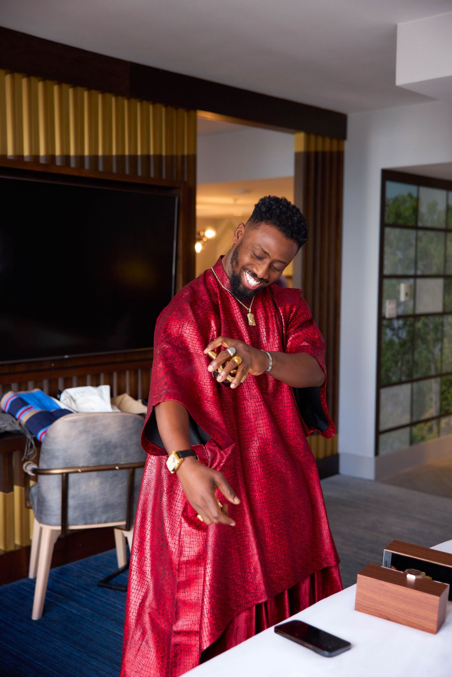 A person in a red robe moves through different gestures and poses in a modern interior setting.