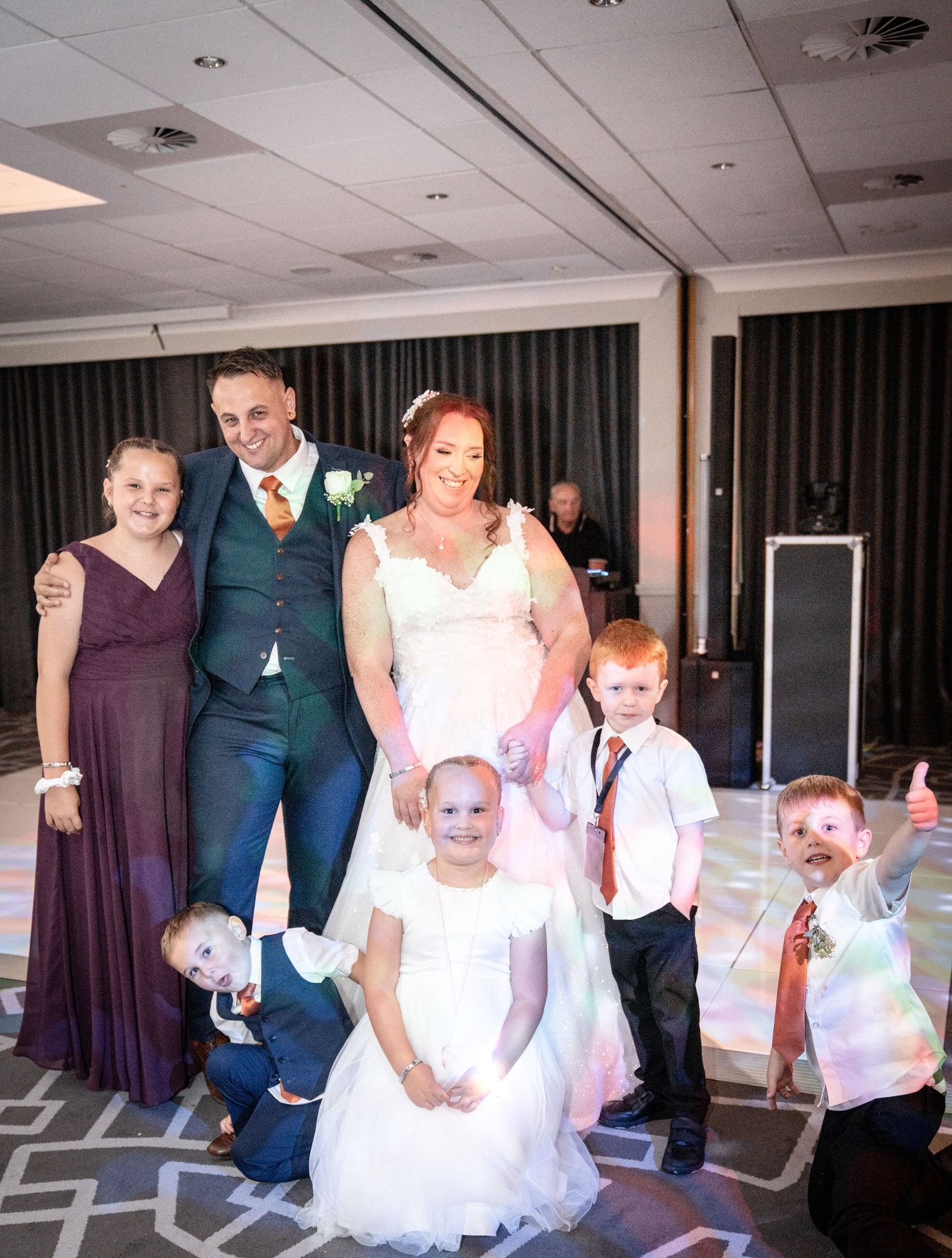Wedding party dancing and celebrating together in a spacious venue with geometric floor patterns.