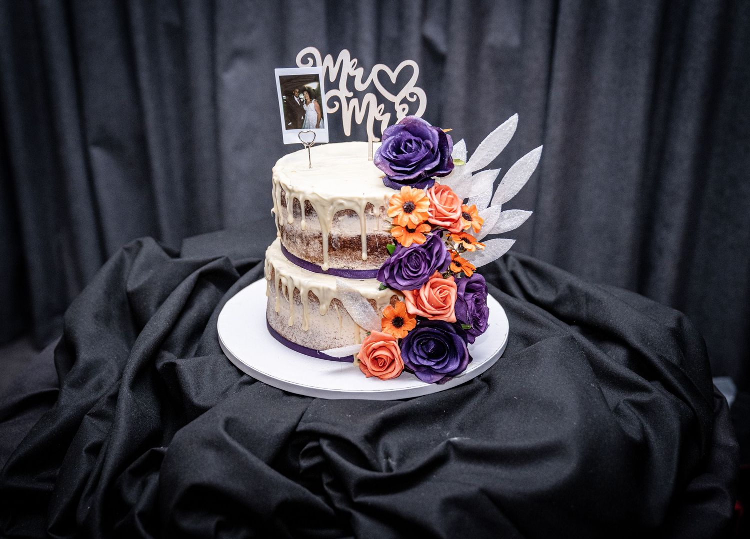 Wedding cakes with purple and orange floral decorations displayed on a black background.