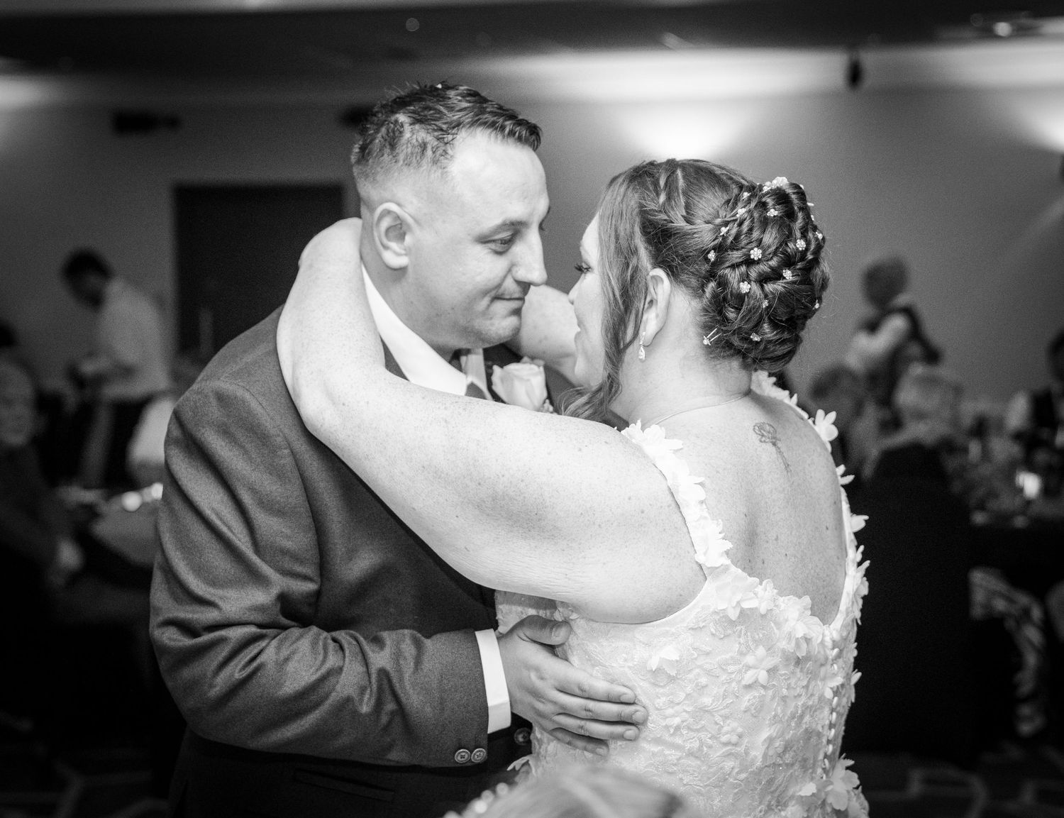 A black and white photo of a couple sharing a romantic dance moment at their wedding celebration.