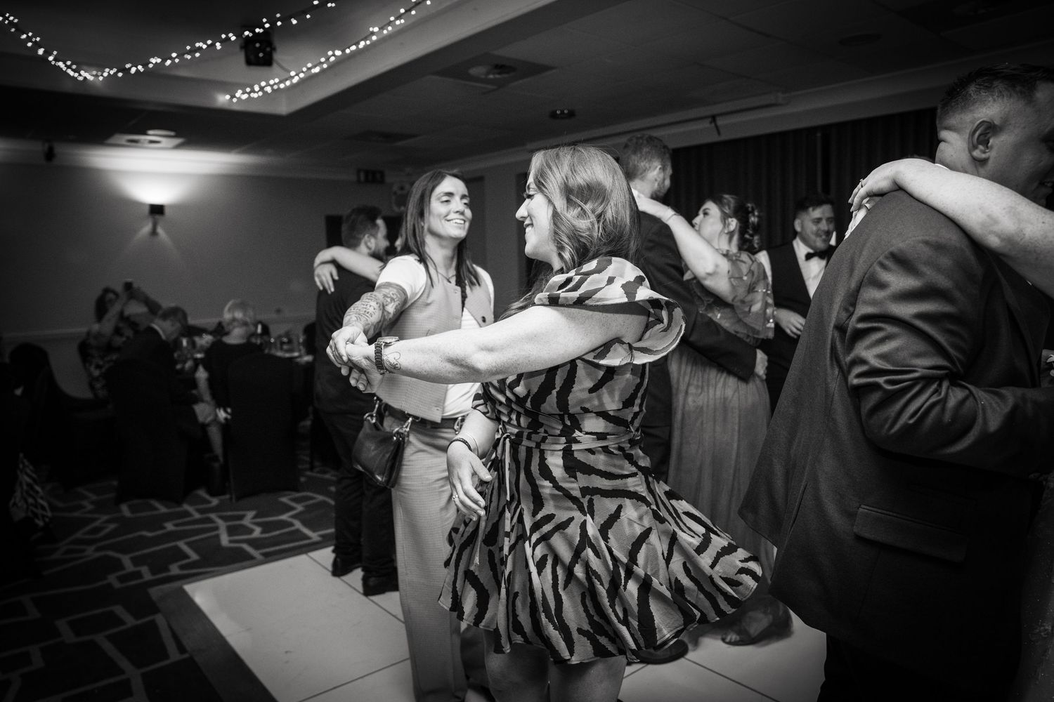 Couple dancing at an elegant ballroom event with dramatic black and white lighting.