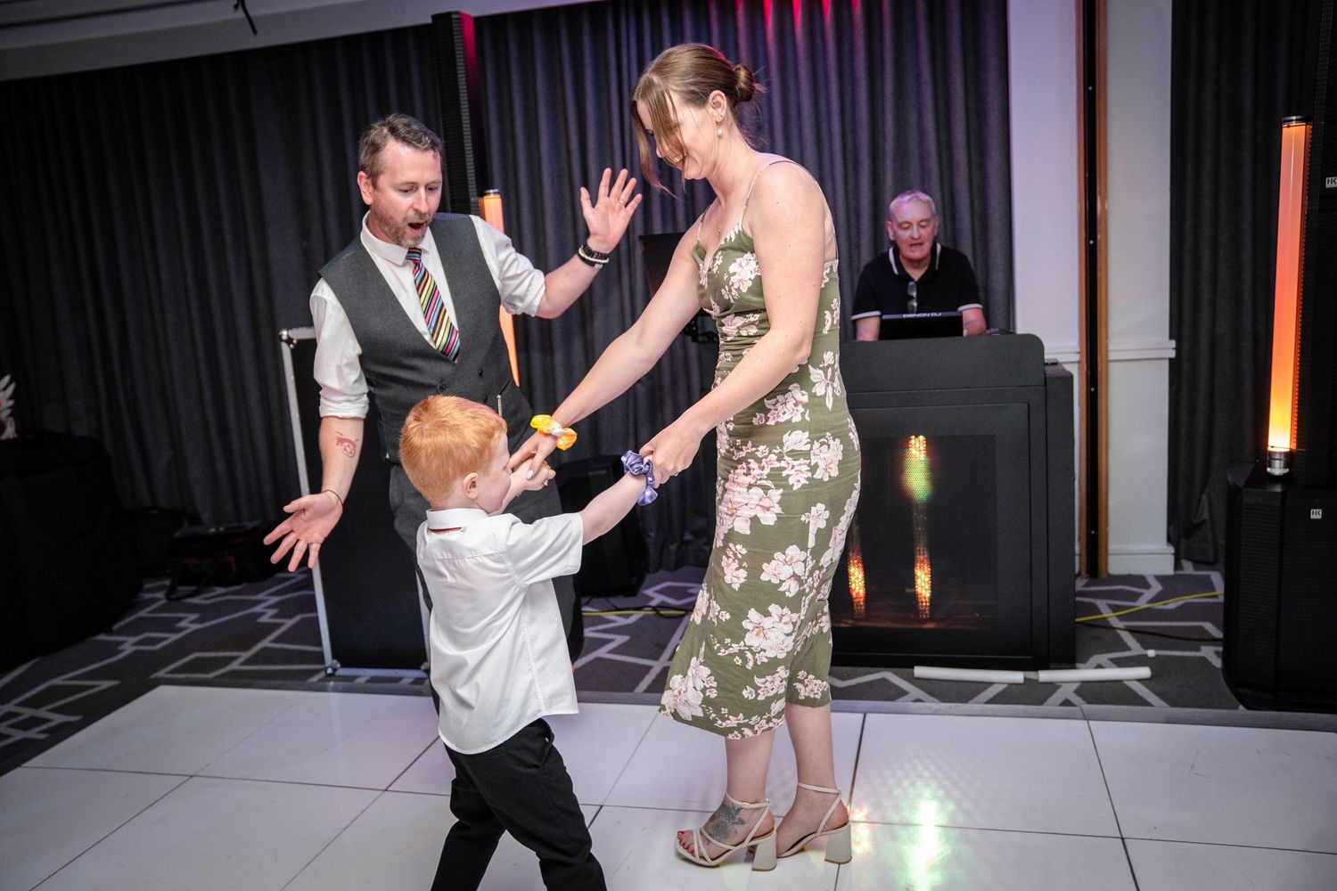 Guests dancing and socializing on a white illuminated dance floor at an evening celebration.