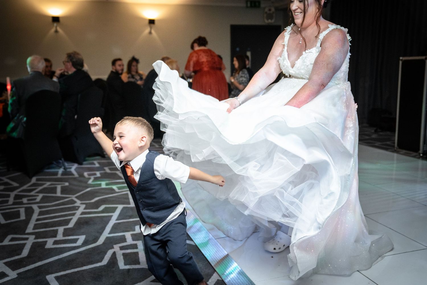 A lively wedding dance party shows guests having fun on the dance floor during an evening reception.