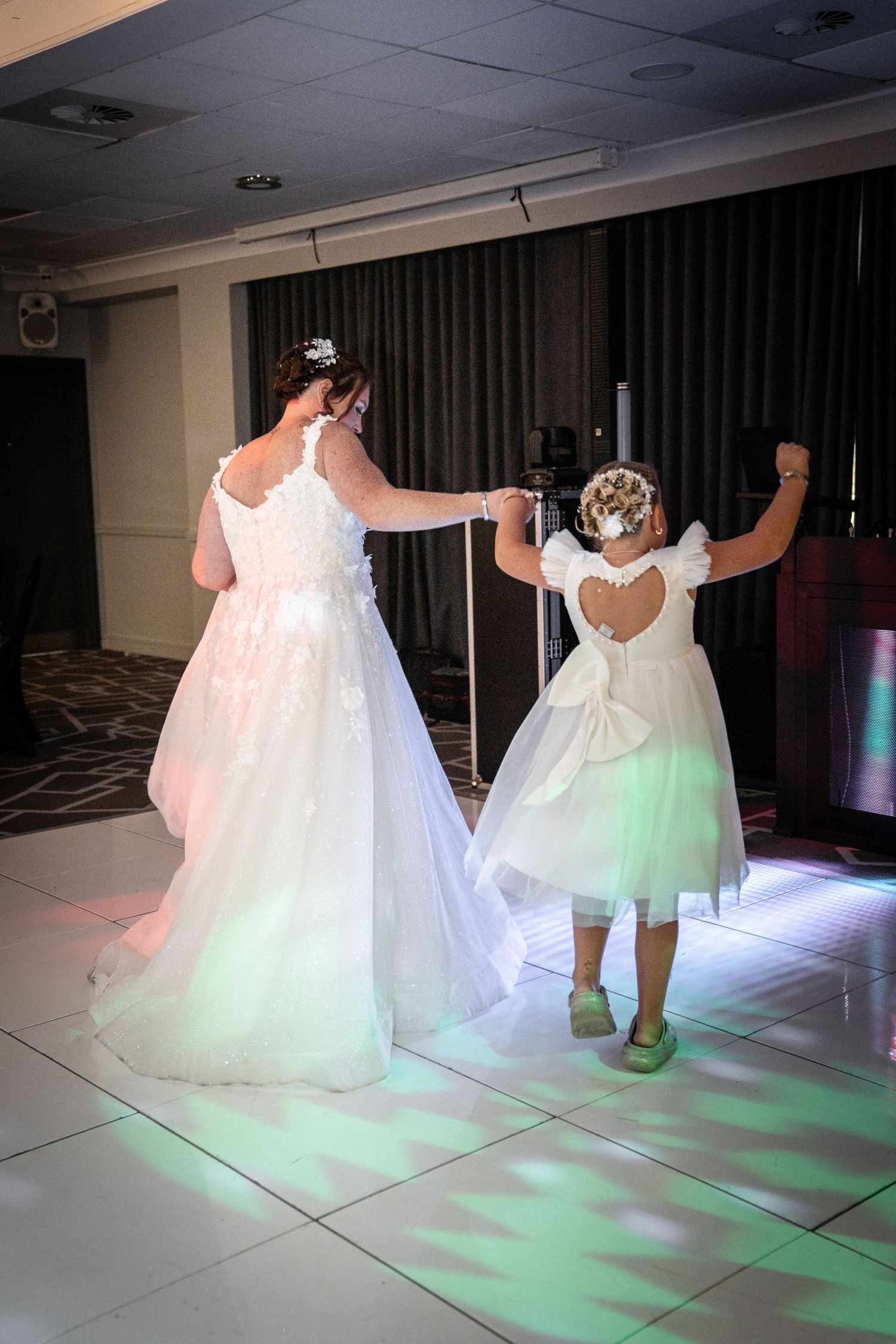 White and mint green dresses swaying on a brightly lit dance floor.