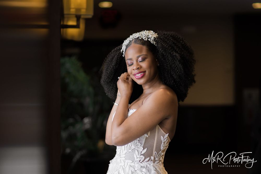 Beautiful Black bride in lace wedding gown with floral headpiece posing with eyes closed.