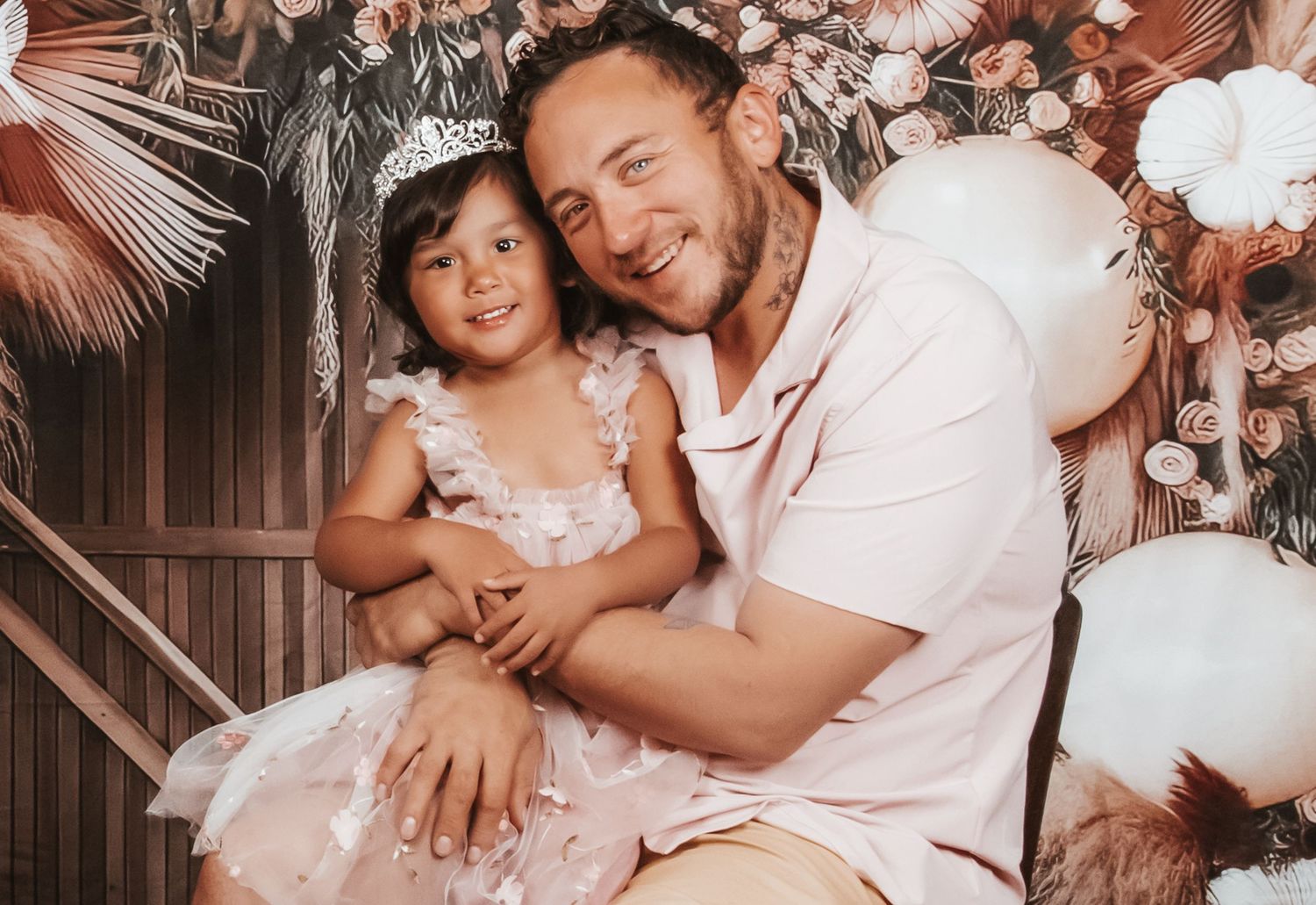 Intimate couple photography session with soft pink lighting and romantic poses against tropical decor.
