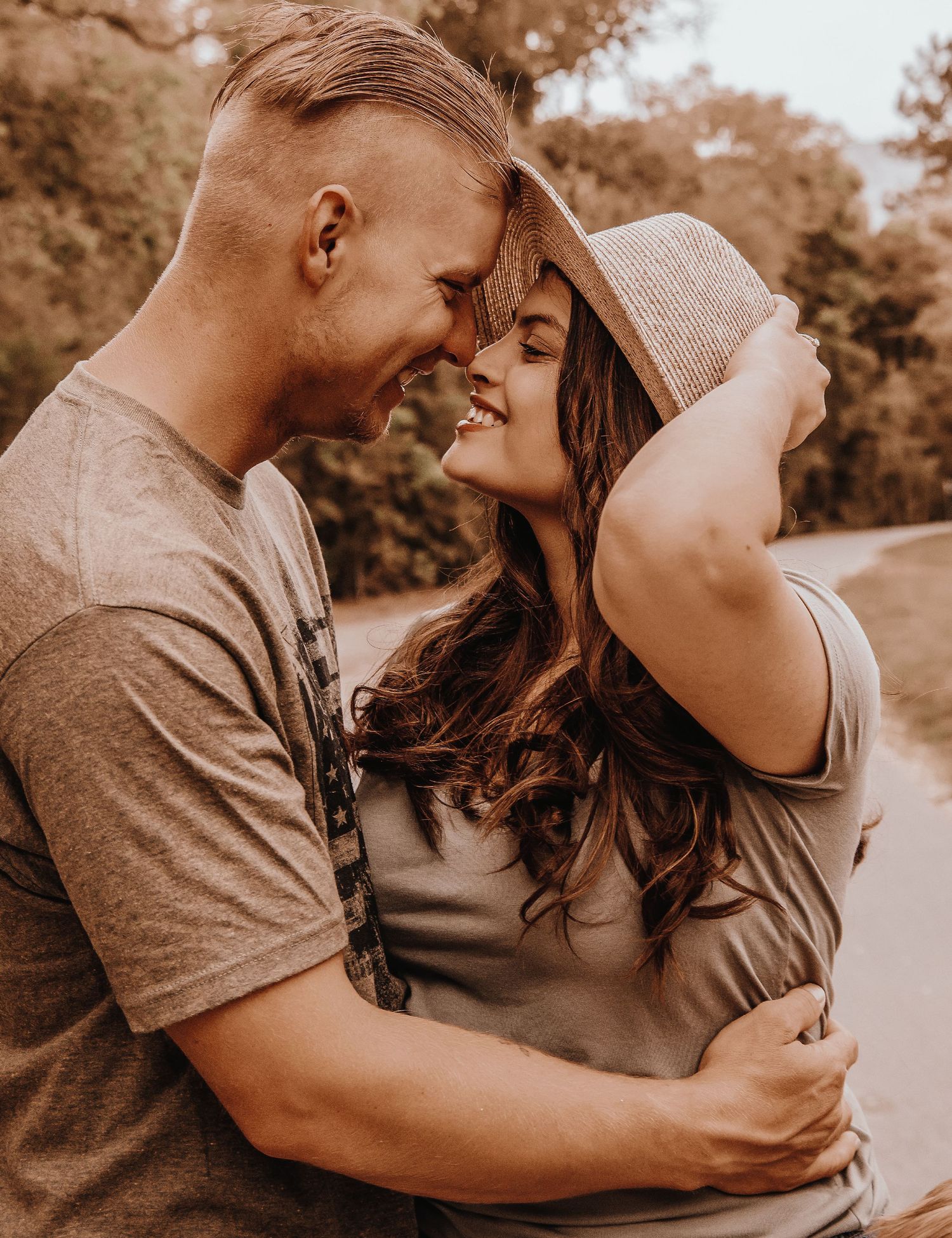 A romantic couple embraces intimately in a sepia-toned outdoor photoshoot sequence.