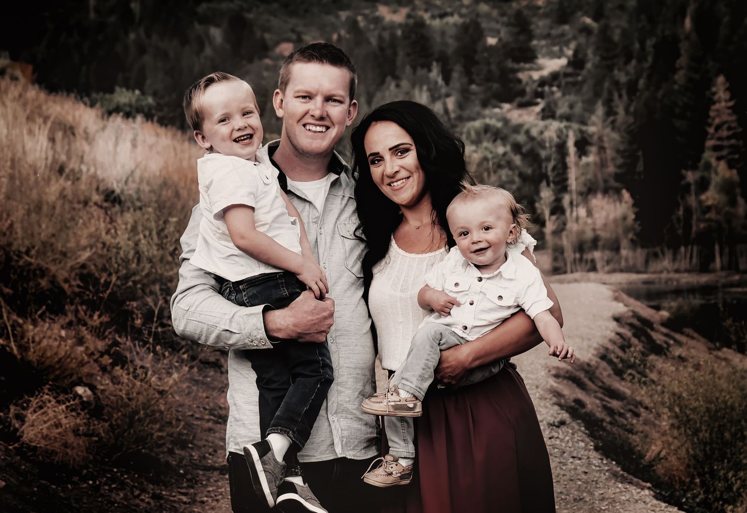 Family portrait session outdoors with warm sepia tones and natural forest backdrop.