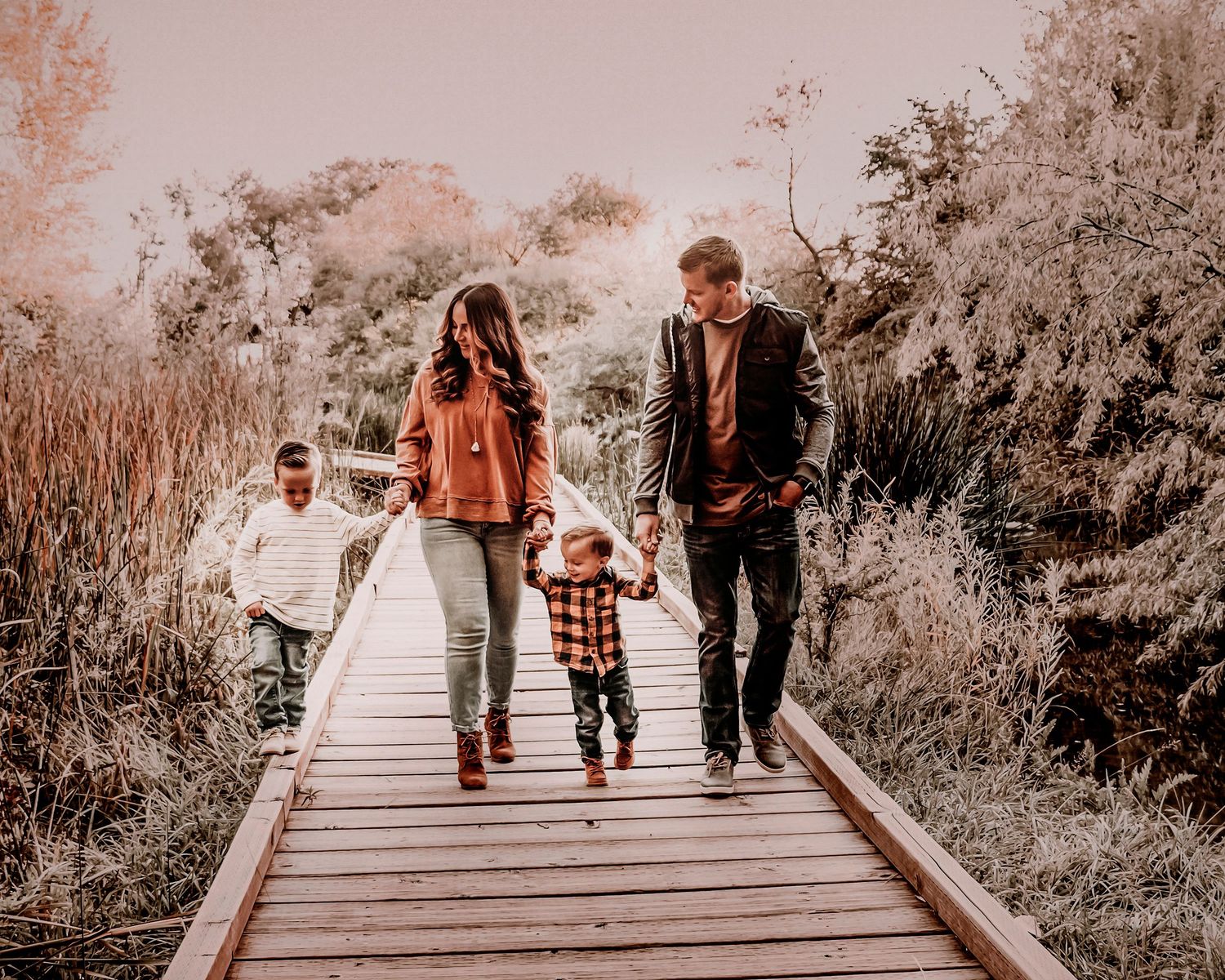 A series of sepia-toned photos showing people walking along a wooden boardwalk path through nature.