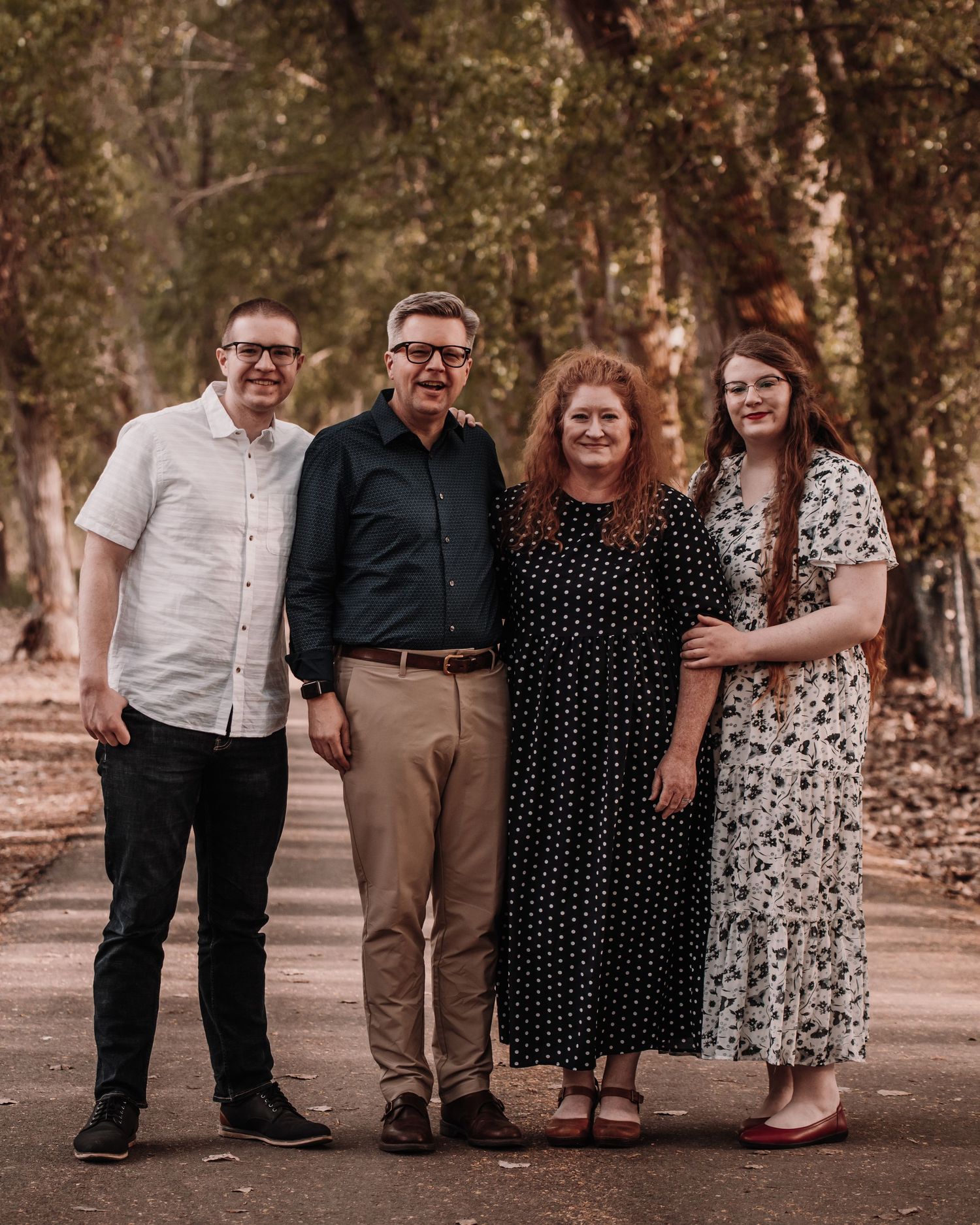 Group photo session in an outdoor wooded setting with warm autumn tones and natural lighting.