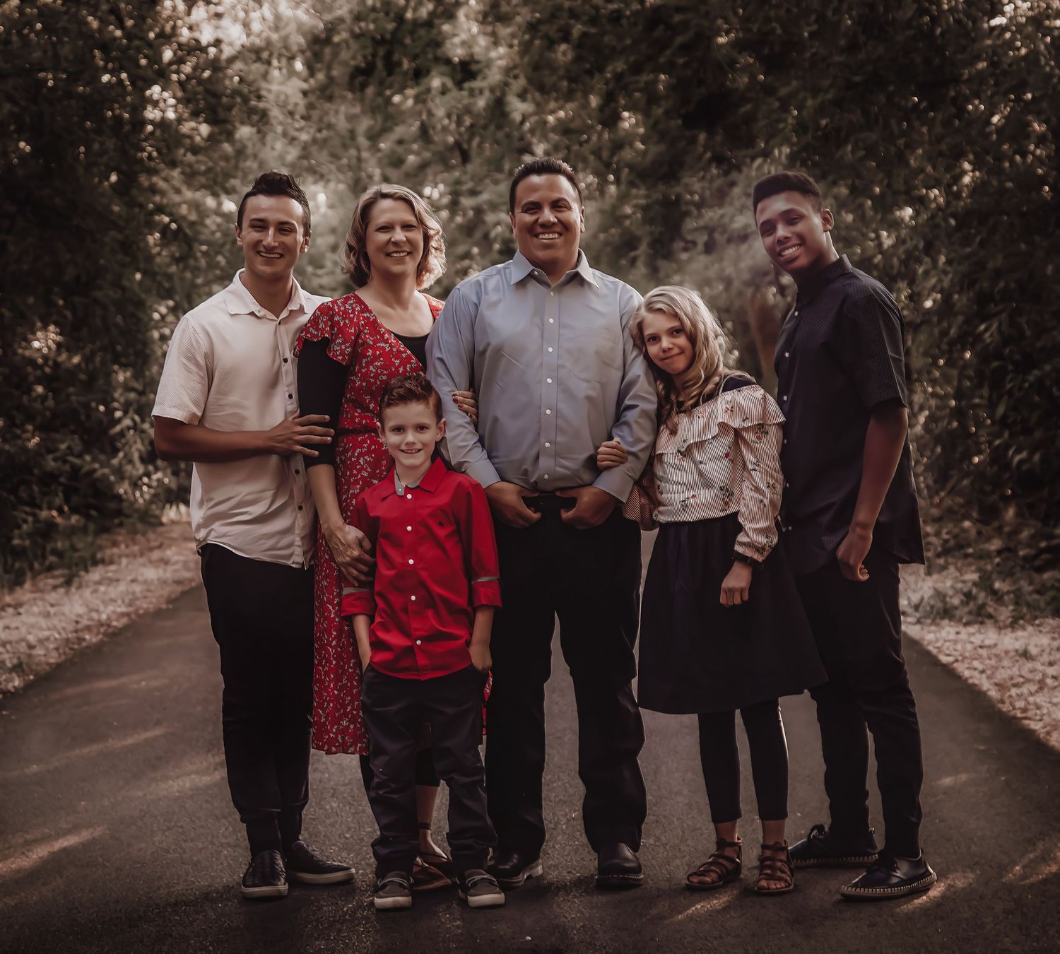 Family gathering outdoors on a path with casual clothing and natural lighting.