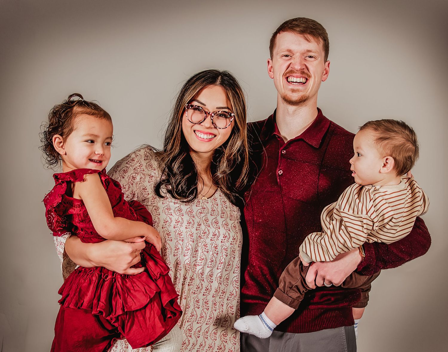 Studio portrait session featuring coordinated burgundy and neutral colored outfits.