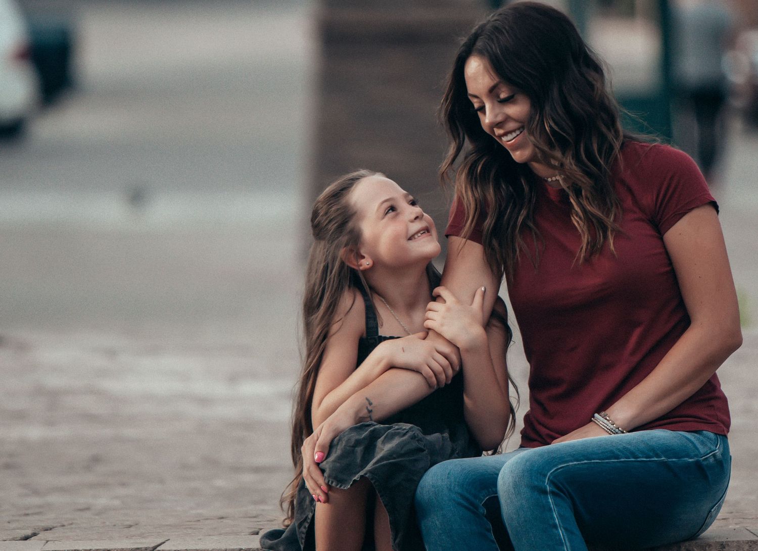 Two people sharing a joyful moment together while sitting outdoors on a sunny day.
