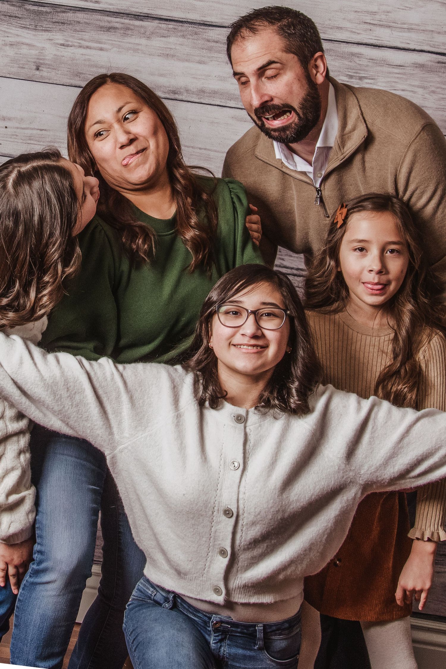 Indoor portrait series showing playful family interactions against a rustic wooden wall background.