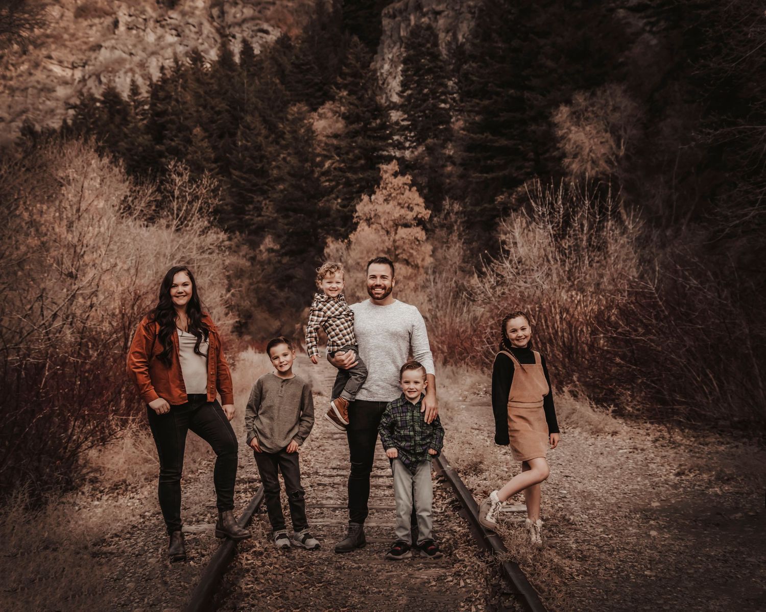 Group photo shoot against a mountainous backdrop with rocky terrain and natural scenery.
