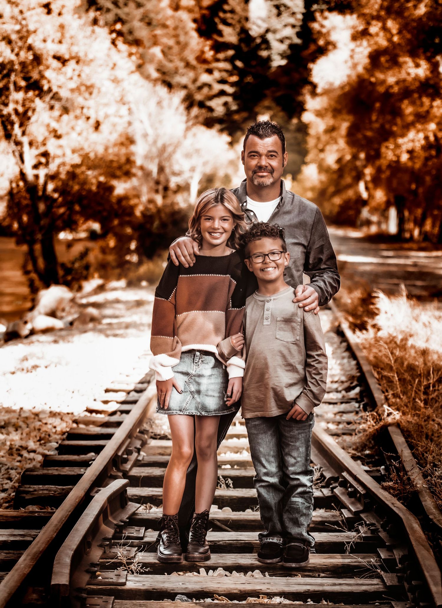 Sepia-toned family photos taken on rustic train tracks showing playful poses and casual interactions.