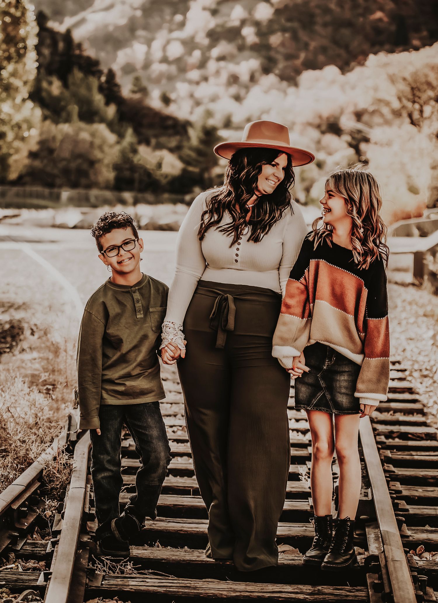 Group portrait session on rustic train tracks with moody lighting and vintage styling.