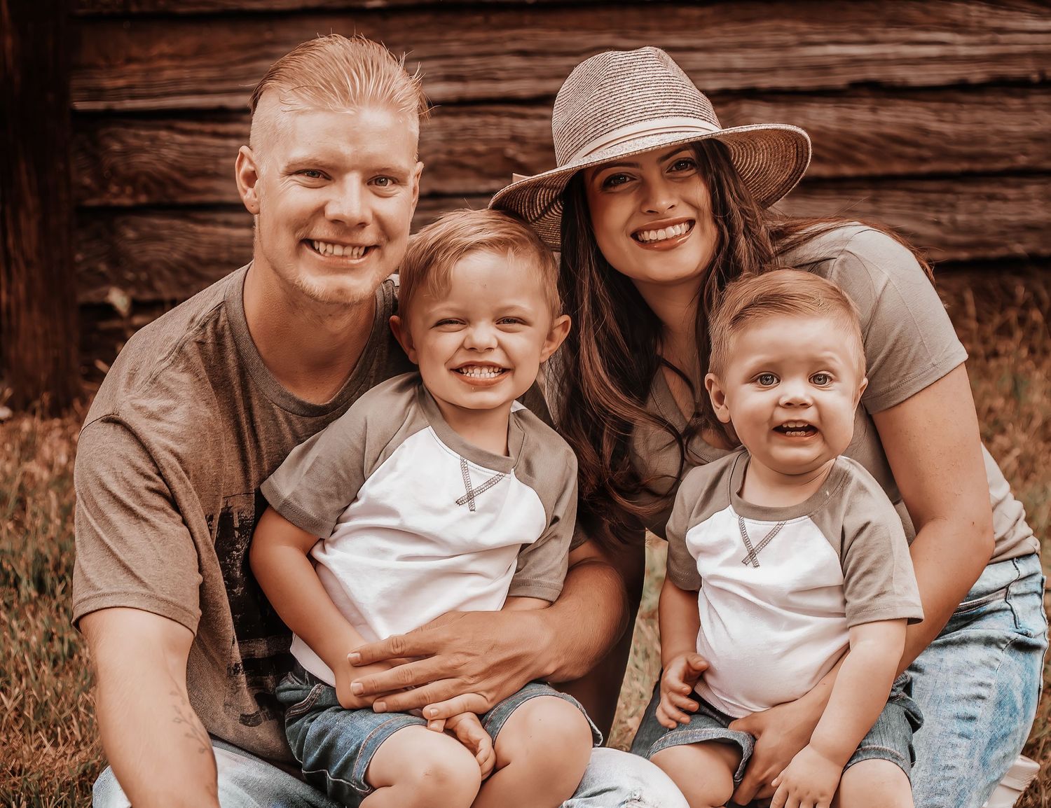 Family sits together on rustic wooden steps during casual outdoor photo session.