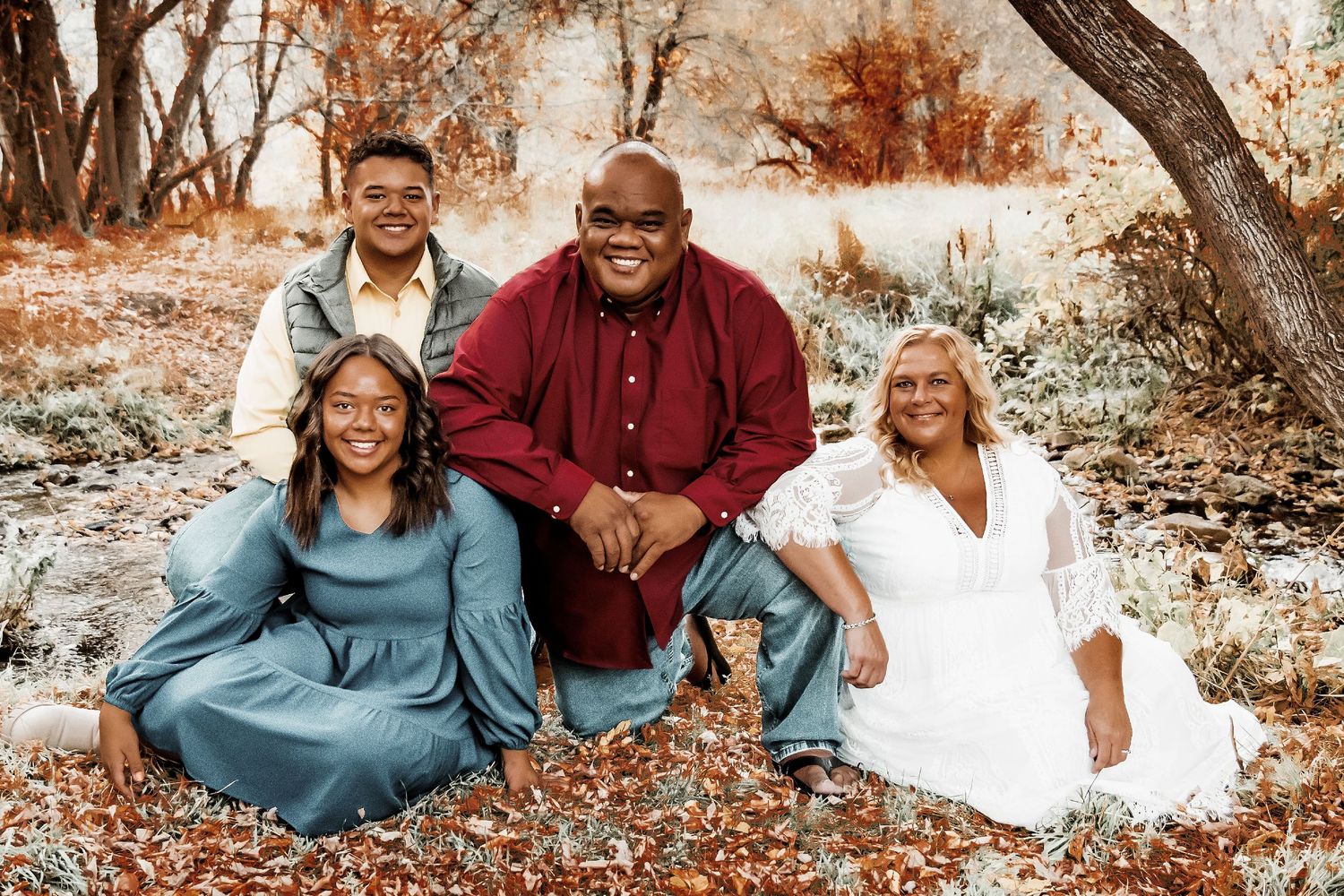 Family group sitting together outdoors during autumn with warm fall colors and natural lighting.