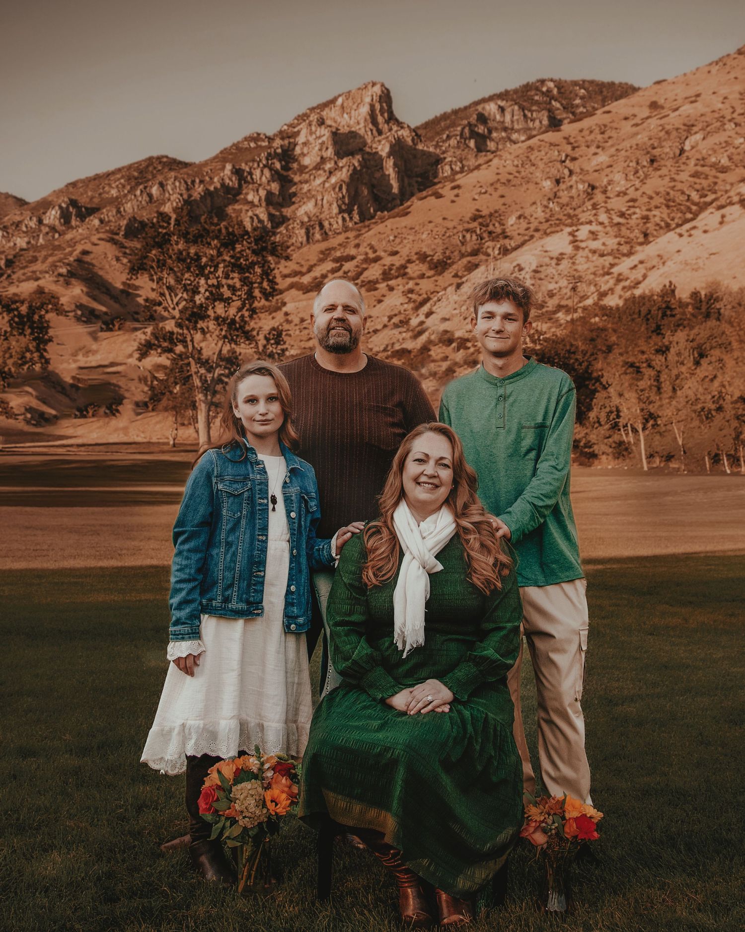A group poses together against a scenic mountain backdrop during a sunset photoshoot.