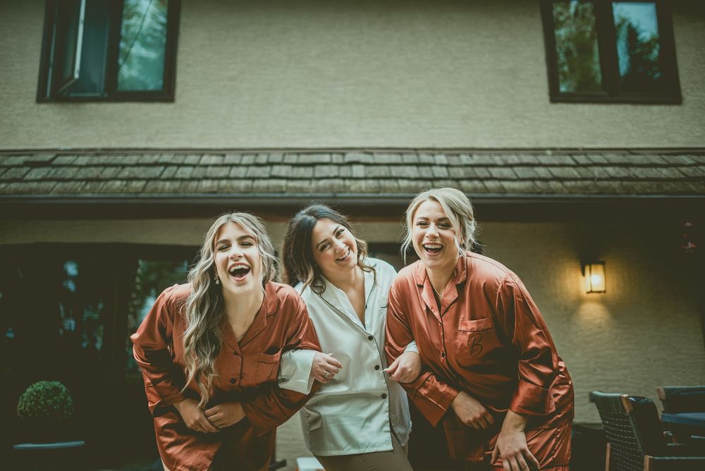 Bridal Party sit close together and share a joyful moment of laughter during sunset. Saskatchewan Wedding Photographer