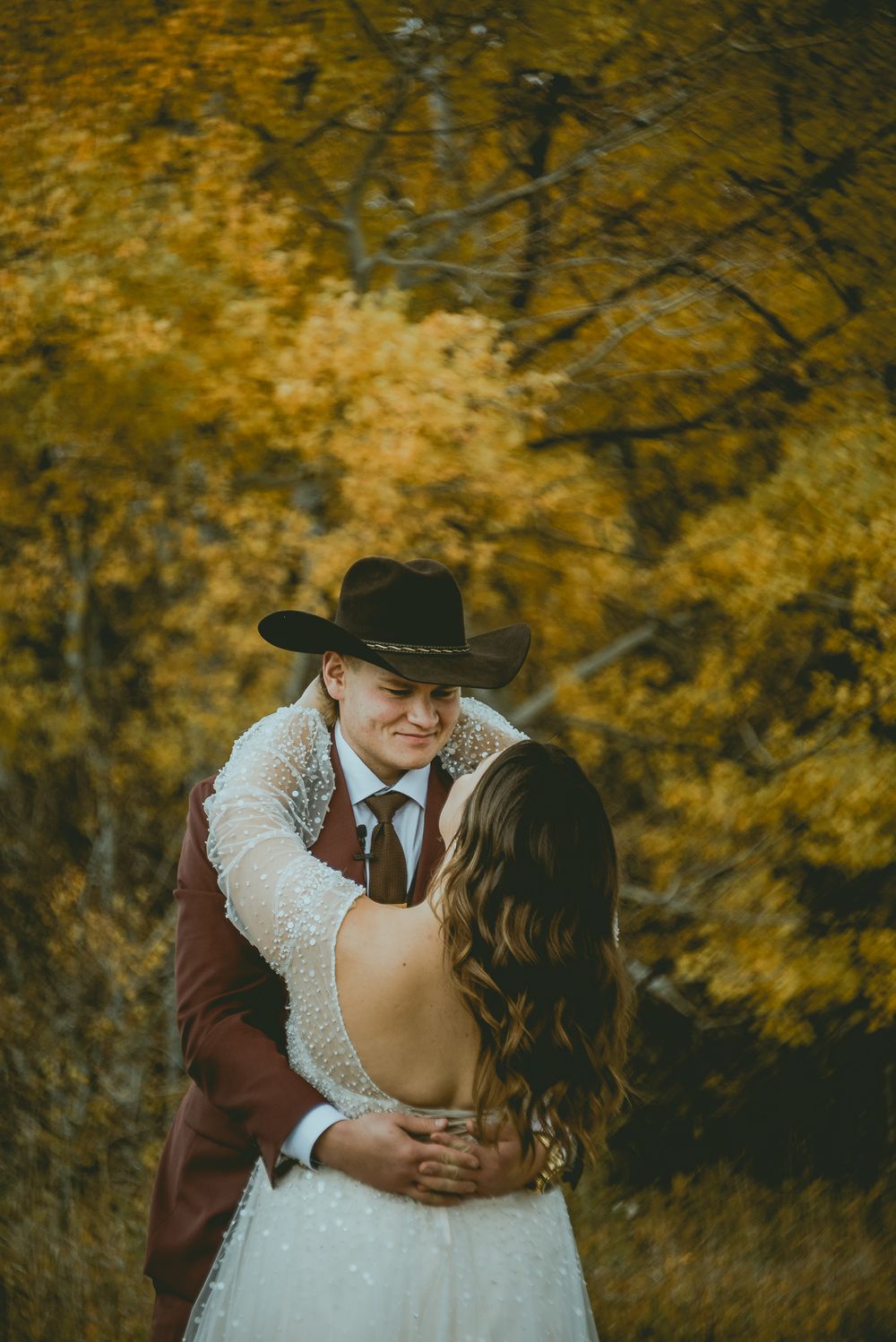 A romantic autumn wedding first look with fall foliage creating a golden backdrop. Saskatchewan Wedding Photographer