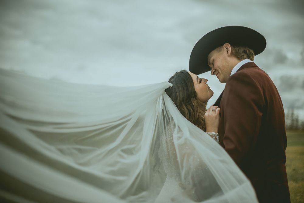A flowing white veil catches the wind during a romantic wedding photo session in moody weather. Saskatchewan Wedding Photographer