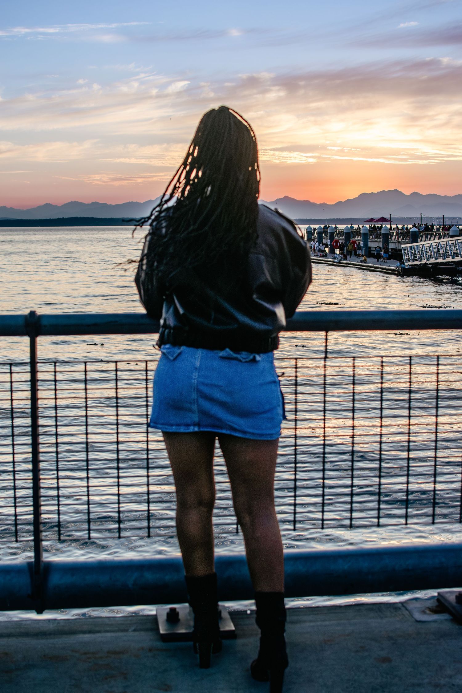 Back view of model in skirt and jacket at Seattle Waterfront overlooking Elliott Bay during sunset portraits.